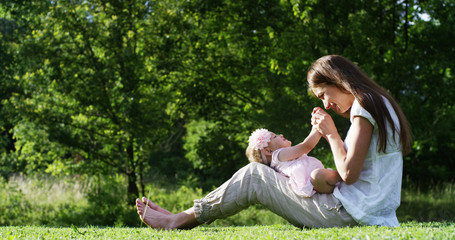 Naklejka na ściany i meble in a beautiful and happy sunny day , a mother and baby little girl play and are happy immersed in the colorful nature and happiness , the baby laughs happy . concept of happiness , love and nature. 