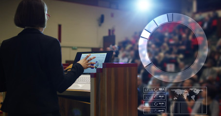 A woman holds a speech to the audience in an auditorium on a convention of economics and finance their business.concept:world economy,futuristic conference, holograms,technology,businessman conference