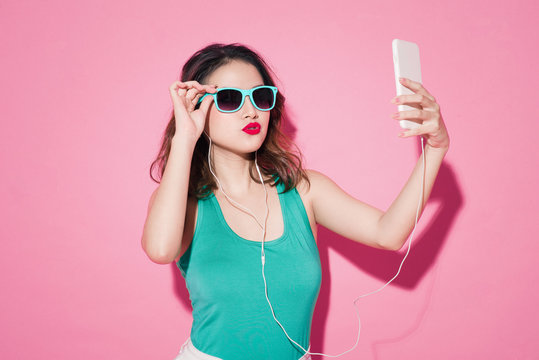 Summer Lady. Beautiful Asian Girl With Professional Makeup And Stylish Hairstyle Taking Selfie Photo On Pink Background.