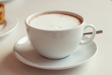 Large coffee mug. Hot chocolate and cheesecake on the table.