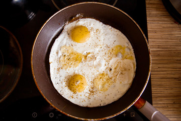 Cooking eggs in a frying pan at home on the stove