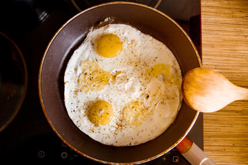 Cooking eggs in a frying pan at home on the stove