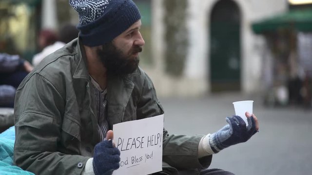 Beggar in the street thanks the pedestrian who leaves him the money
