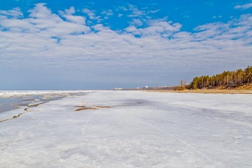 Spring melting of ice on the Volga River against the background of mountains and blue sky