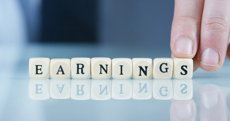 Slow motion macro of the word "Earnings" of the wooden letter blocks . Concept of financial market and future of stock market business.
