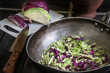 Green and Purple cabbage on pan with knife on black wood.