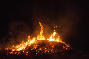 Fototapeta na wymiar burning bonfire at night with flames reaching into the dark sky