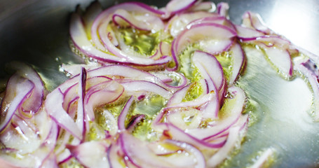 Obraz premium Slow motion of chef cutting the onion in small slices on a wooden table of a professional kitchen, concept of Italian and Mediterranean diet , diet concept and healthy life 