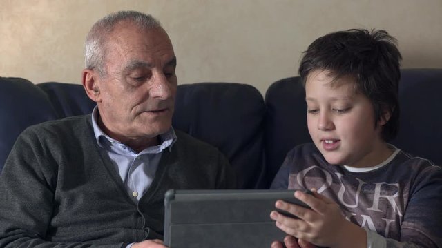 close up on  grandfather with grandson using tablet on couch