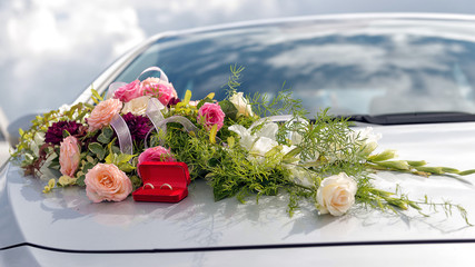 Flower decoration and a ring set on gray wedding car bonnet.