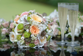 Bridal bouquet and champagne glasses on wedding car bonnet.