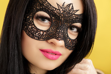 portrait of beautiful sensual woman in black lace mask on yellow background. sexy girl in venetian mask