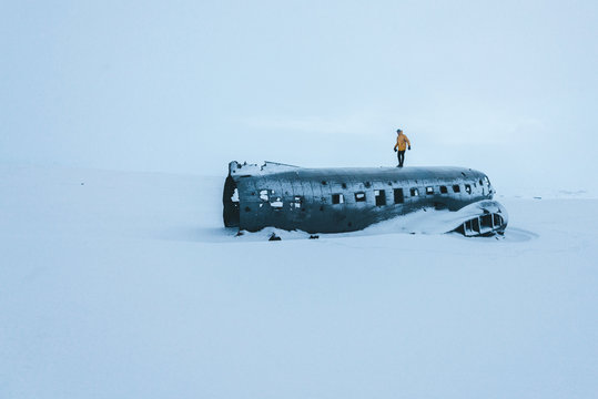Person in yellow jacket walking on a plane wreckage in the snow