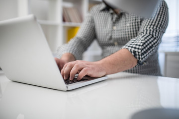 Cropped photo of a man's hands using laptop in office