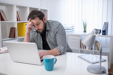 Handsome businessman working hard with laptop in office