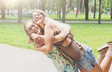 Two happy young girls hug each other in summer park