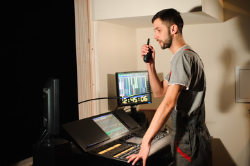 A lighting engineer works with lights technicians control on the concert show. Professional light...