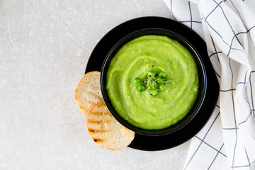Homemade puree soup with green peas and micro greens. selective focus