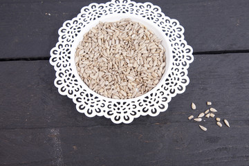 Sunflower seeds in white bowl on wooden background