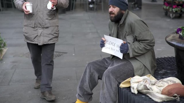 Hungry homeless receives breakfast from an elderly man