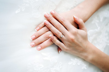 Obraz na płótnie Canvas Hand of the bride with a ring on a white dress.
