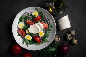 Italian salad prepared with arugula, mozzarella, eggs. Black background