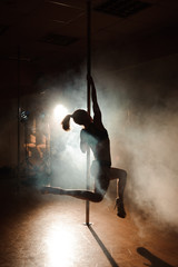Naklejka na ściany i meble Young sexy woman exercise pole dance on a dark background