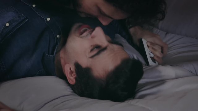 Close up gay couple on the bed who lit and then kisses gently
