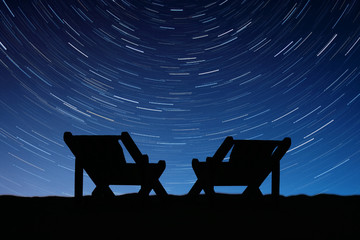 The silhouettes of the chairs on the background of star tracks