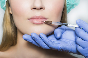 Doctor aesthetician makes lips correction and augmentation to female patient