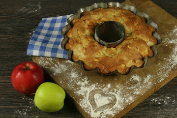 Homemade apple pie with a knitted cloth on wooden table