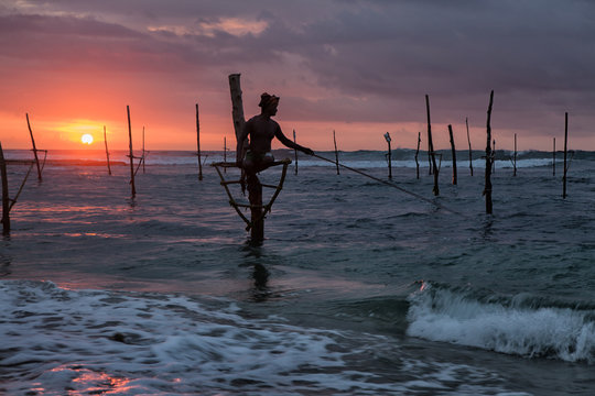 Силуэт рыбака на фоне океана и заката.