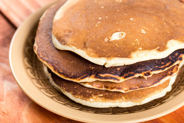 Closeup macro of american pancakes stacked on the plate over rustic wooden background table