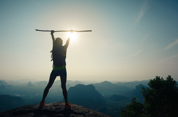 cheering successful woman hiker open arms on sunrise mountain top