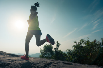 silhouette of young woman running on sunrise mountain peak