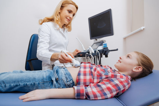 Friendly sonographer providing ultrasound abdomen examination at work