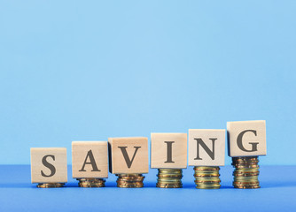 SAVING concept with wooden blocks, coins on table.