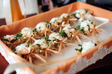 On the tray are many small floral ornaments for the wedding