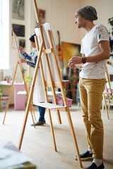 Obraz premium Learner of art-school standing by easel