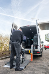 Driver Assisting Disabled Man To Board Wheelchair Lift Van