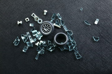 Plastic model of aluminum alloy wheel among broken tempered glass represent the damaged abstract...