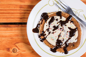 Flat lay closeup macro american pancake with cream colorful sprinkles and topped chocolate cream