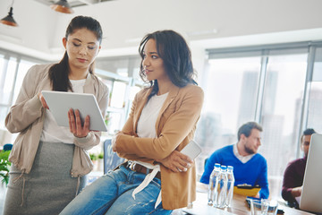 Female coworkers doing research on digital tablet .