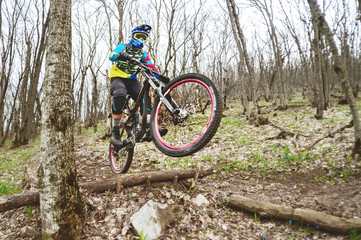 A mountain bike rider jumps from a springboard in a foggy forest, in the Caucasus Mountains