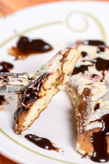 Slice of american pancake topped with chocolate cream and sprinkles on the fork closeup macro