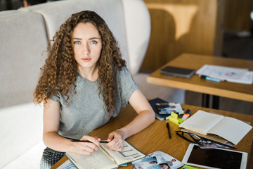 Fototapeta premium Young serious businesswoman looking at camera while planning her work
