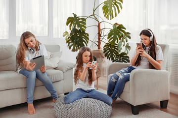 Group of teenage girls is using gadgets. Kids with phones and ta