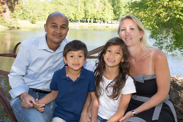 family sitting by the water with a father of Indian origin and a blond mother with blue eyes Caucasian