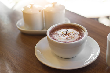Cocoa drink in white cup on wooden background