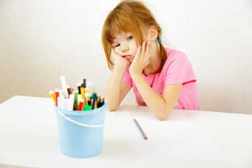 Bored girl over blank piece of paper and pencils